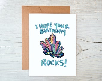 May include: A white card with a colorful illustration of a crystal cluster. The text on the card reads "I hope your birthday rocks!"