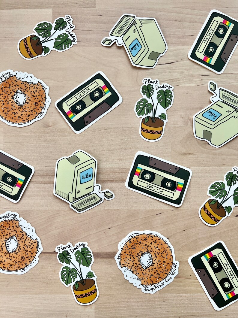 May include: A collection of stickers featuring a retro computer, cassette tapes, bagels, and potted plants. The stickers have a hand-drawn style with text that reads "hello", "MIX TAPE", "Plant Daddy", and "you're my everything". The color palette includes beige, brown, green, and black.