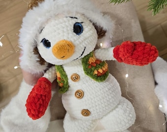 Puede incluir: Muñeco de nieve de ganchillo hecho a mano con cuerpo blanco, sombrero marrón con ribete blanco, chaleco verde y naranja y mitones rojos. El muñeco de nieve tiene una nariz de zanahoria, ojos azules y una cara sonriente. Decoración invernal.