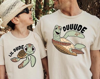 May include: Two matching t-shirts featuring a cartoon sea turtle. The larger shirt says "DUUUDE" and the smaller shirt says "LIL DUDE".
