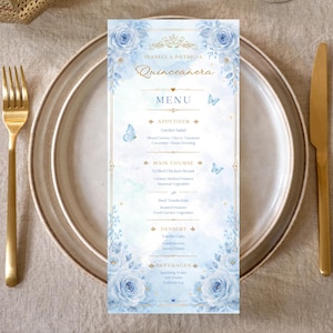 May include: A vertical rectangular menu card for a Quinceañera featuring blue watercolor roses, gold filigree accents, and light blue butterflies. The text reads Isabella Patricia Quinceañera, Menu, Appetizer, Main Course, Dessert, and Beverages.