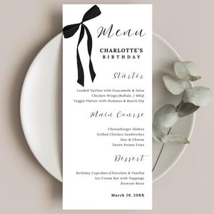 Puede incluir: Una tarjeta de menú blanca con texto negro y un lazo negro. El menú enumera entrantes, platos principales y postres para el cumpleaños de Charlotte. La fecha es el 29 de marzo de 20XX. El menú está en un plato blanco con una ramita de vegetación.