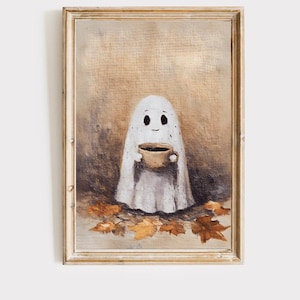 May include: A framed print featuring a friendly ghost holding a small brown cup. The ghost is draped in a white sheet, with a simple face. Autumn leaves are scattered at the ghost's feet, set against a neutral background.