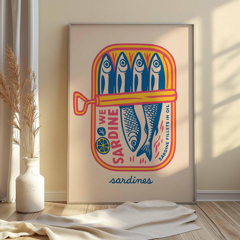 May include: A framed print featuring a colorful illustration of a sardine can. The can is yellow and pink, with blue fish inside. Text on the can reads "WE SARDINE" and "SARDINE FILLETS IN OIL". The word "sardines" is written in blue at the bottom.