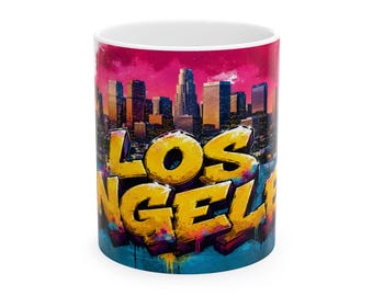May include: White ceramic mug with a colourful design of the Los Angeles skyline. The words "LOS ANGELES" are in large, yellow 3D lettering. The background transitions from a deep pink to a teal blue.