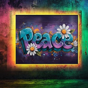Könnte beinhalten: Ein gerahmtes Kunstwerk mit dem Wort "Peace" im Graffiti-Stil, mit blauen und lila Buchstaben und weißen Gänseblümchen-Akzenten. Der Hintergrund ist ein dunkles Lila mit bunten Farbspritzern, vor einer strukturierten Wand.