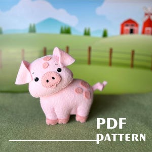 Op de afbeelding: Een roze vilt varken met bruine ogen en een roze neus. Het varken heeft een paar bruine vlekken op zijn lichaam. Het varken staat op een groene ondergrond met de tekst "PDF PATTERN" in witte letters.
