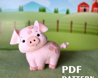 May include: A pink felt pig with brown eyes and a pink nose. The pig has a few brown spots on its body. The pig is standing on a green surface with the text "PDF PATTERN" in white letters.
