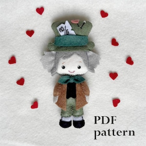 Puede incluir: Un patrón de muñeca de fieltro del Sombrerero Loco de Alicia en el País de las Maravillas. El patrón incluye un sombrero verde con una carta de juego 10/6, una chaqueta marrón y una corbata de lazo verde. El patrón está disponible para descargar en PDF.