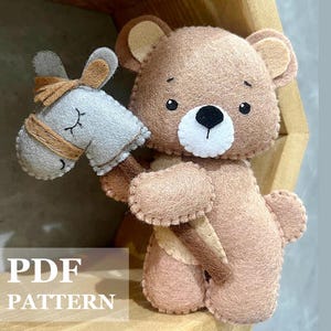 Può includere: Un modello PDF per un set di giocattoli in feltro con un orso marrone che tiene un cavallo a dondolo grigio e marrone. L'orso ha un muso bianco e occhi neri. Il cavallo a dondolo ha una criniera e una coda marroni.