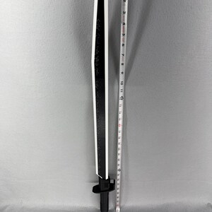 May include: A black and white decorative sword with a straight blade. The sword is approximately 36 inches long. The blade has a black surface with white edges and a white stripe down the center. The handle is black.