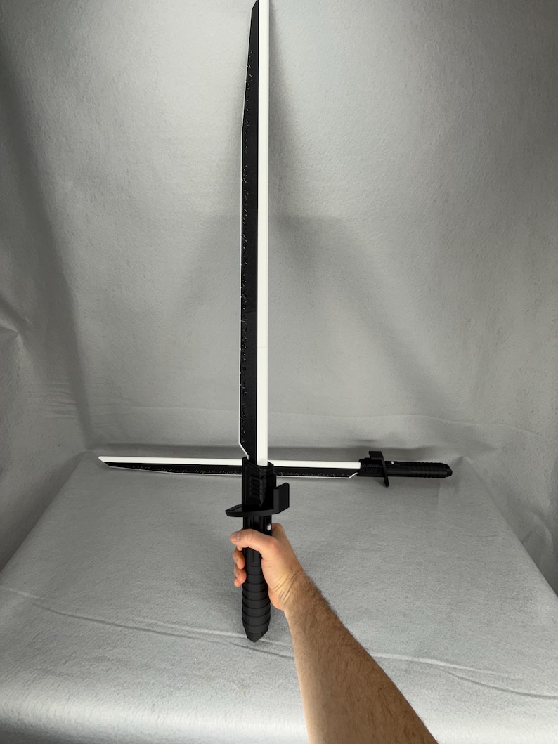 May include: A black and white sword with a crossguard and a textured handle. The blade is white with a black edge and a black spine. The sword is held in a hand.