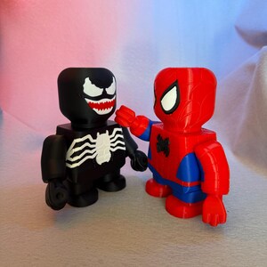 May include: Black and white Venom and red and blue Spider-Man action figures. Both figures are standing and facing each other.