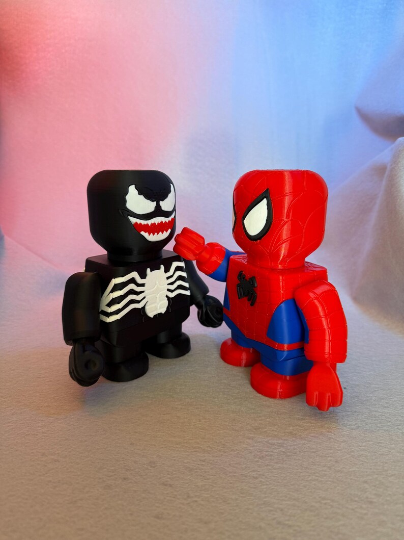 May include: Black and white Venom and red and blue Spider-Man action figures. Both figures are standing and facing each other.