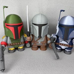 May include: Three Star Wars action figures, each with a unique helmet design. The figures are holding weapons and are posed in a standing position. The figures are green, gray, and blue.