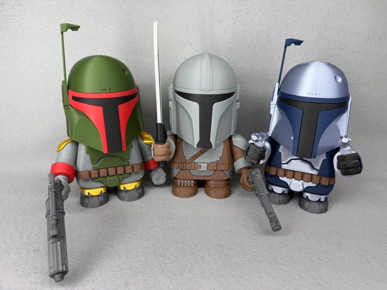 May include: Three Star Wars action figures, each with a unique helmet design. The figures are holding weapons and are posed in a standing position. The figures are green, gray, and blue.