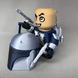 May include: A blue and silver action figure of a Star Wars character holding a silver weapon. The figure is wearing a helmet and has a blue and silver jetpack.
