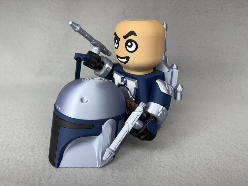 May include: A blue and silver action figure of a Star Wars character holding a silver weapon. The figure is wearing a helmet and has a blue and silver jetpack.