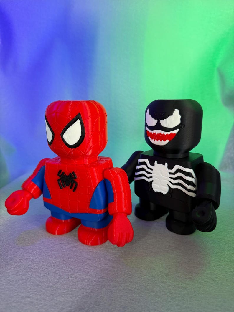 May include: Red and blue Spider-Man figurine standing next to a black Venom figurine. Both figurines have a blocky design.