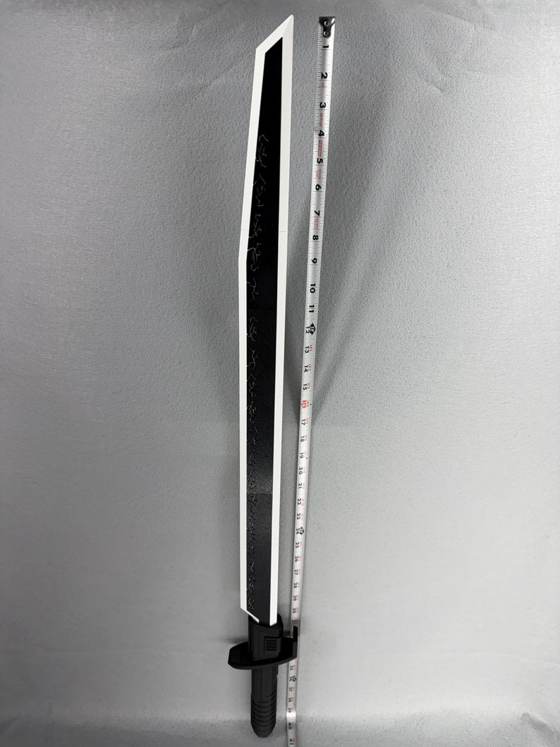 May include: A black and white sword with a straight blade. The blade has a white edge and is approximately 24 inches long. The handle is black and has a guard. The sword has etched markings on the blade.