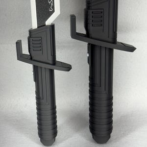 May include: Two black and white toy light sabers. The hilts are black with a ribbed design, and the blades are white with a black textured top. One blade has a lightning bolt design. The hilts have a crossguard.