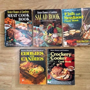 Könnte beinhalten: Eine Sammlung von fünf Vintage-Kochbüchern von Better Homes & Gardens mit bunten Covern, die Food-Fotografie zeigen. Die Titel lauten "Meat Cook Book", "Salad Book", "Fish and Seafood Cook Book", "Cookies and Candies" und "Crockery Cooker Cook Book".