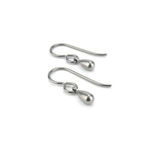 Peut inclure: Une paire de boucles d'oreilles argentées en forme de goutte. Chaque boucle d'oreille est dotée d'un crochet incurvé et d'un petit pendentif lisse en forme de goutte. Les boucles d'oreilles sont présentées sur fond blanc.