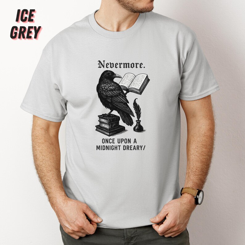 May include: Ice grey t-shirt featuring a black raven illustration with the text "Nevermore" and "Once Upon a Midnight Dreary/". The raven is perched on books, holding a book and quill.