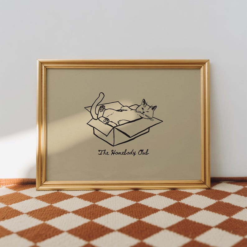 Minimal black line drawing of a cat lounging in a box, styled as a funny cat poster with homebody decor charm for a cozy book nook poster space, text reads “The Homebody Club”.