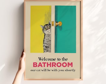May include: A framed print with a whimsical illustration. A gray tabby cat peeks from behind a yellow and teal door. Text reads "Welcome to the BATHROOM our cat will be with you shortly."