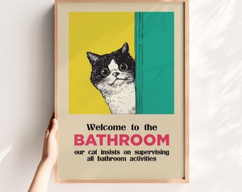May include: Framed art print featuring a black and white cat peeking from behind a teal and yellow background. The text reads "Welcome to the BATHROOM our cat insists on supervising all bathroom activities."