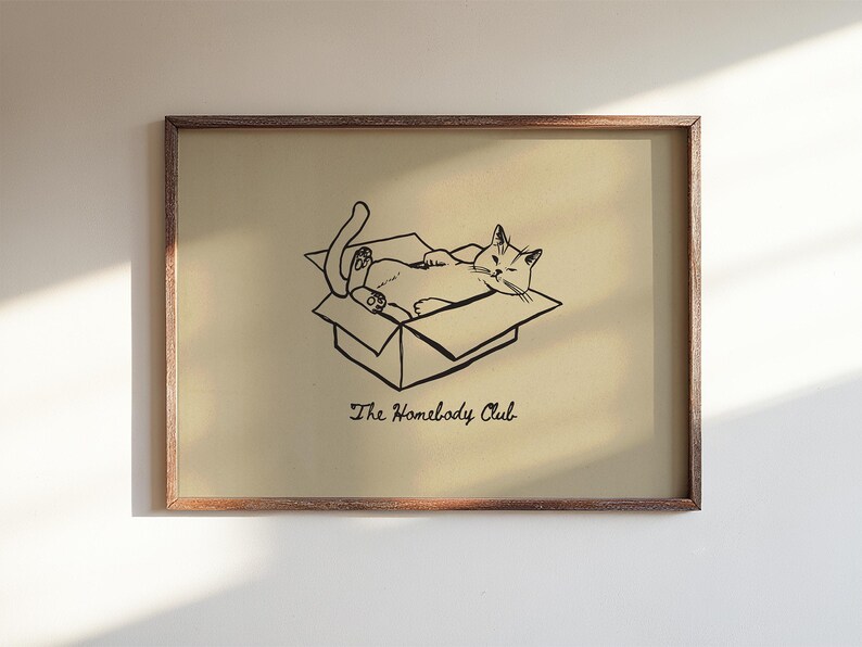 Minimal black line drawing of a cat lounging in a box, styled as a funny cat poster with homebody decor charm for a cozy book nook poster space, text reads “The Homebody Club”.