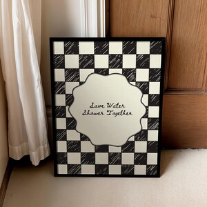 Funny "Save Water, Shower Together" bathroom wall art featuring a hand-drawn red and cream checkered pattern in a retro indie aesthetic.
