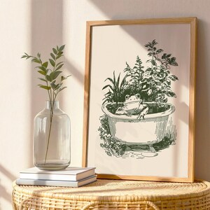 Ink-style drawing of a frog relaxing in a bathtub surrounded by leafy plants, with a soft vintage cottagecore look. Neutral simple art for guest bathroom decor.