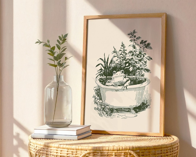 Ink-style drawing of a frog relaxing in a bathtub surrounded by leafy plants, with a soft vintage cottagecore look. Neutral simple art for guest bathroom decor.