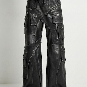 May include: Black leather pants with multiple pockets and zippers. The pants have a wide-leg design and feature a unique wrap-around detail. The brand name "VELVISTACO" is visible at the top. These pants are a statement piece for a bold, edgy look.