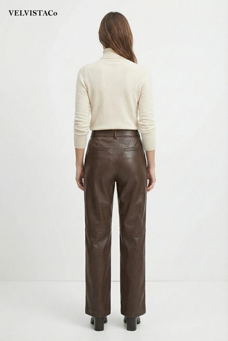 May include: A person is shown from the back, wearing a cream-colored turtleneck sweater and brown leather pants. The pants are high-waisted with a straight leg. The outfit is simple and classic, suitable for various occasions.
