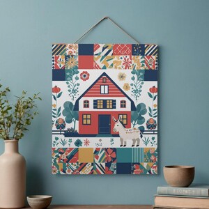 Könnte beinhalten: Ein dekoratives Wandbild mit einer farbenfrohen Illustration eines roten Hauses mit einem weißen Esel. Das Kunstwerk hat ein Patchwork-Design mit floralen und geometrischen Mustern in Rot, Blau, Gelb und Grün.
