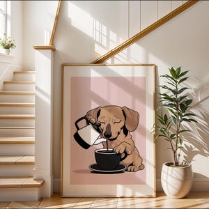 Puede incluir: Una impresión artística enmarcada que presenta un perro salchicha de dibujos animados vertiendo café en una taza negra. El perro es de color marrón claro, y el fondo es de un rosa suave. La impresión está en un marco dorado.