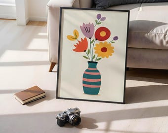 May include: A framed art print featuring a colorful floral arrangement in a teal vase with pink stripes. The flowers are in shades of red, orange, yellow, and purple. A brown notebook and a vintage camera are in the foreground.
