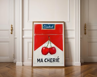 May include: A framed art print featuring a red and white design reminiscent of a cigarette pack, with two cherries and the text "MA CHERIE". The top of the print has the word "Cieubel". The artwork is displayed on a wooden floor.