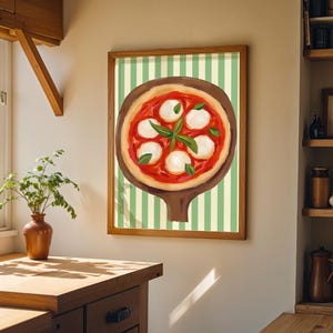 May include: A framed print of a pizza on a wooden peel, set against a green and white striped background. The pizza features a red sauce, white mozzarella cheese, and basil leaves. The artwork is displayed in a kitchen setting.