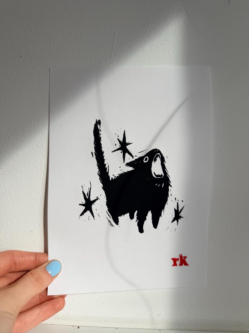 May include: Black and white art print of a screaming cat with star accents. The cat is silhouetted against a white background. The artist's initials, "rk", are in red in the lower right corner.