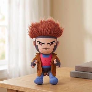 May include: A plush toy character featuring spiky reddish-brown hair, red eyes, and a brown trench coat over a pink and blue outfit. The figure has a determined facial expression with a light beard, fingerless gloves, and blue boots.