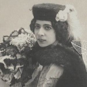 Postal antigua de una joven elegante con volantes, pieles y plumas