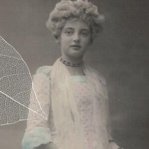 Belle fille des années 1920 en costume à volants rose clair et bleu avec éventail privé