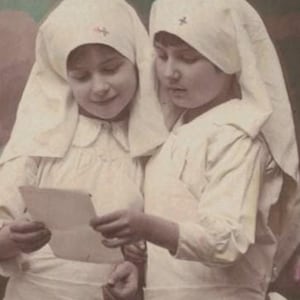 1915 Niñas disfrazadas de enfermeras leyendo una carta de reconocimiento