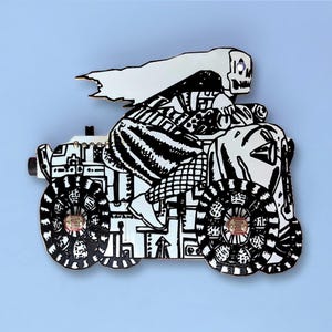 May include: A black and white pin depicting a skeleton riding a motorcycle. The pin has intricate details, including the skeleton's skull, flowing hair, and the motorcycle's wheels and body. The background is a light blue.