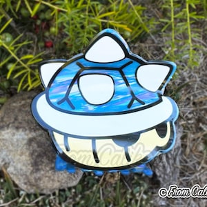 May include: A blue and white sticker featuring a cartoon character with a white belly, blue body, and white accents. The sticker has a black outline and the text "From Caliko" in the bottom right corner.