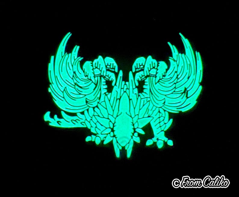 May include: A glowing teal emblem against a black background. The design features a symmetrical, stylized bird or mythical creature with detailed wings and a central body. The text "From Caliko" is in the bottom right corner.